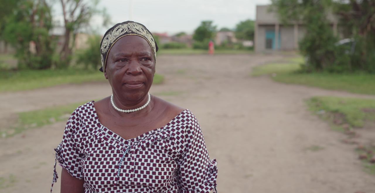 A woman in a patterned dress walks down a rural road