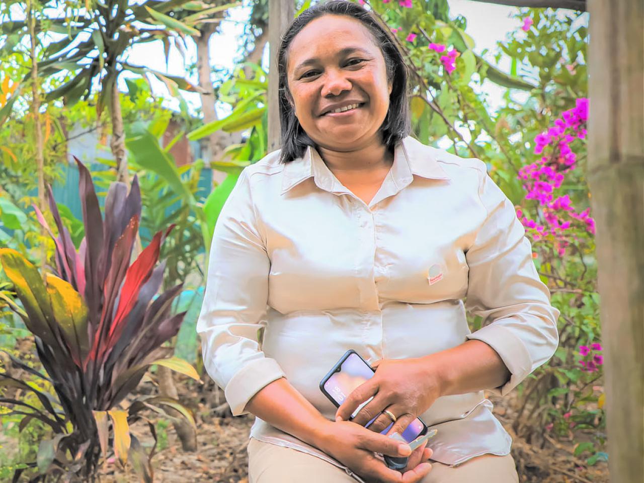 A smiling woman stands in front of garden