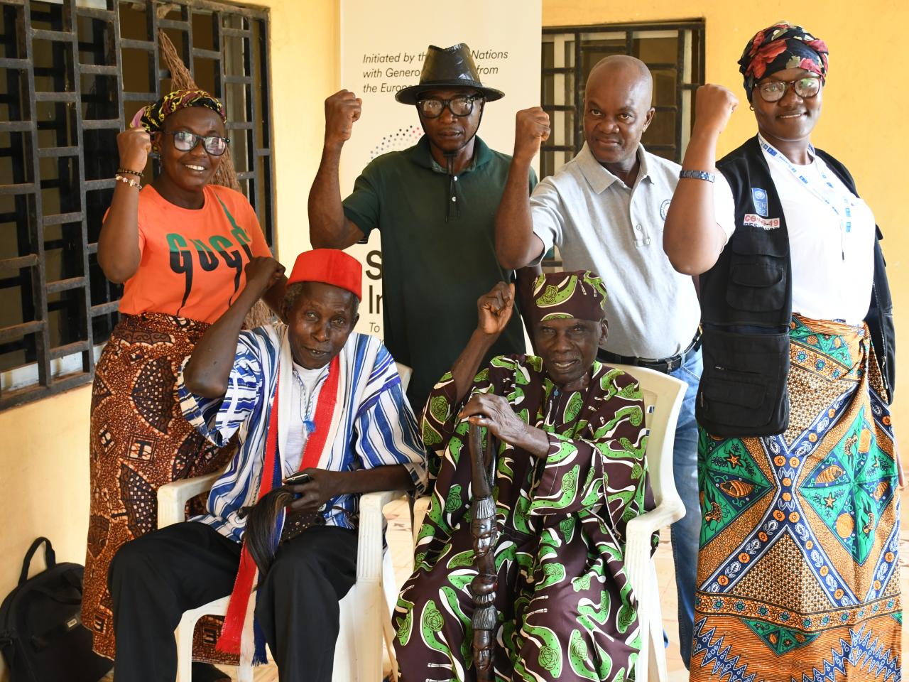 Five men and women smiling and raising fists in the air