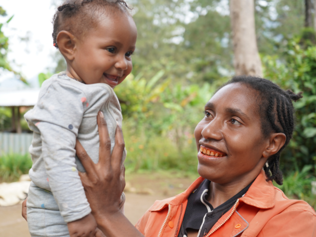 A smiling mother holds he laughing baby