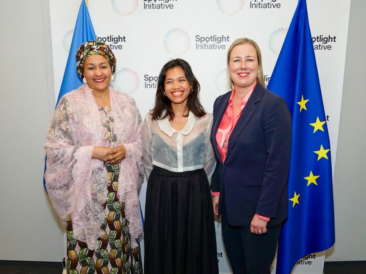 Three women stand in front of flags