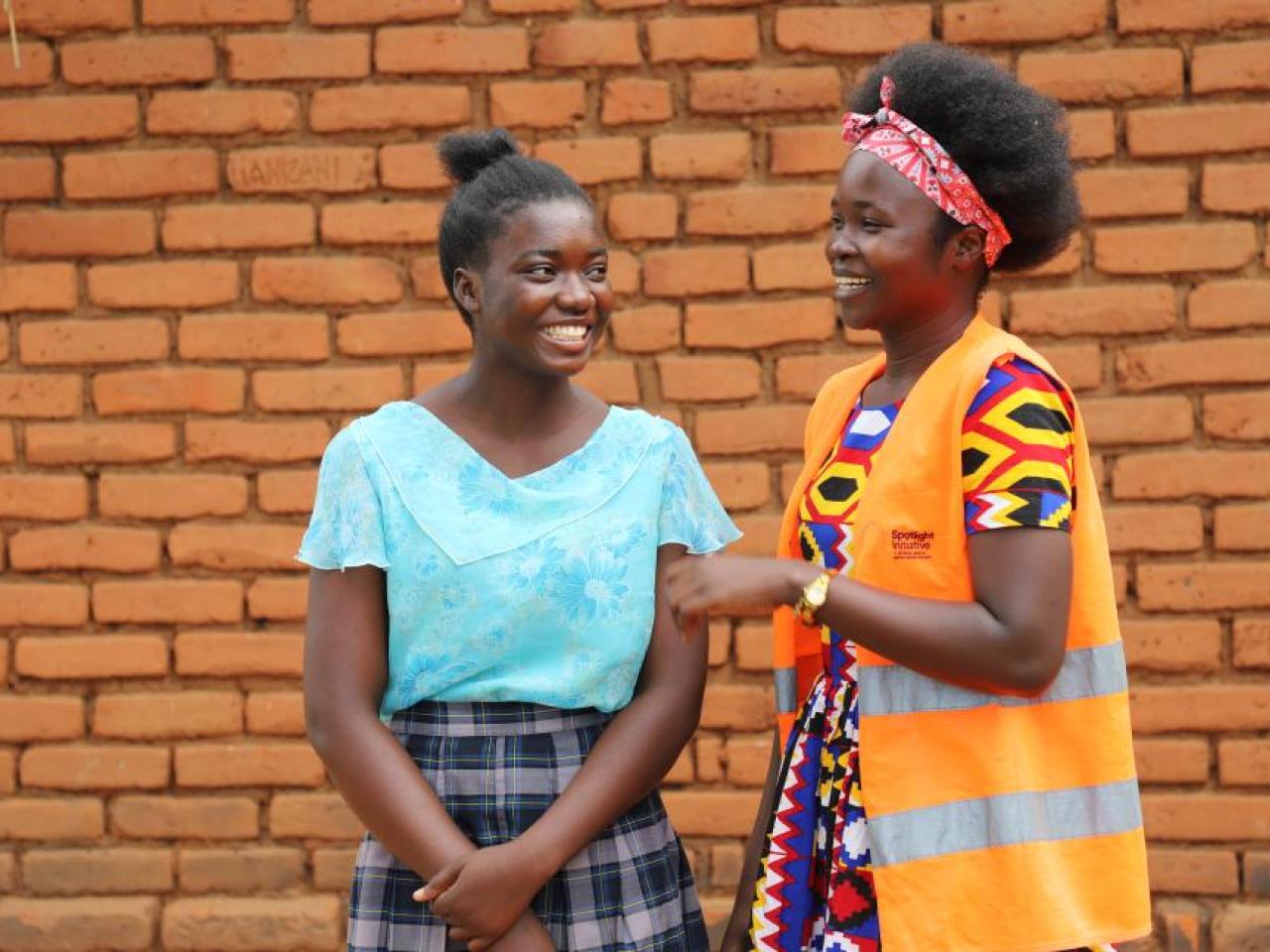 Two smiling girls chat, one wears an orange high visibility vest