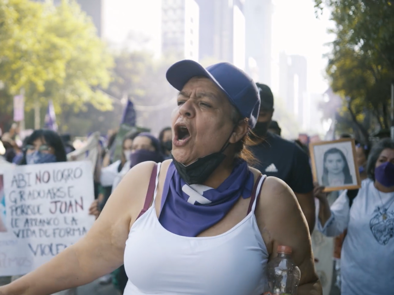 A woman in purple hat and scarf shouts and leads a march