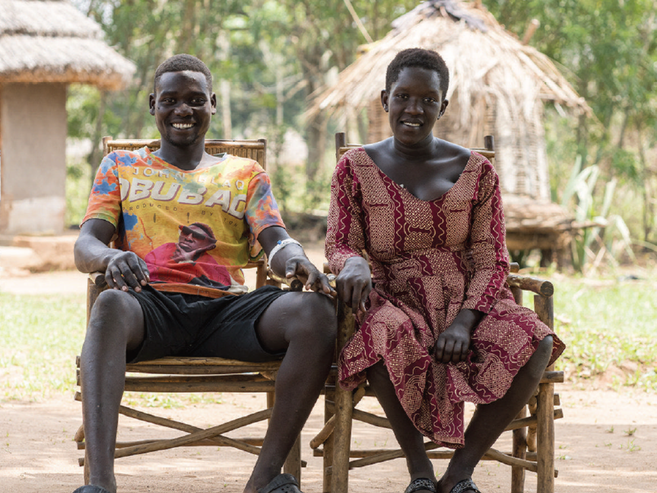 A man and a woman are seated, smiling and holding hands