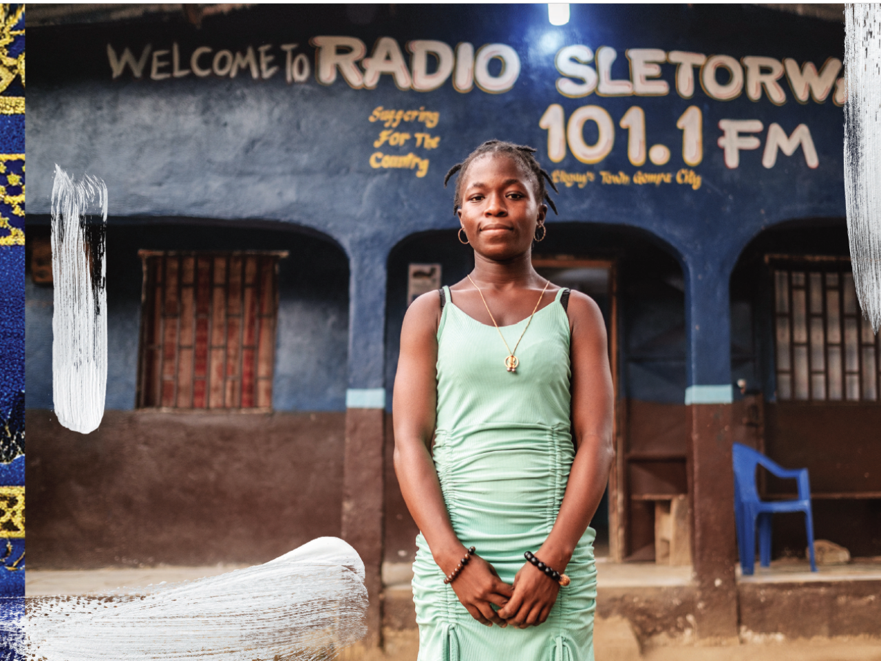 A woman in a green dress stands outside a building that reads Radio Sletorwah