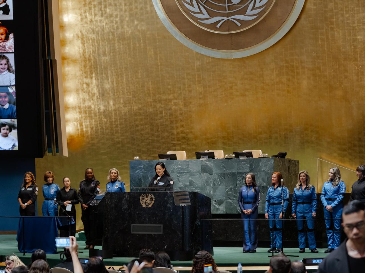 Women in astronaut suits stand at the front of the UN general assembly
