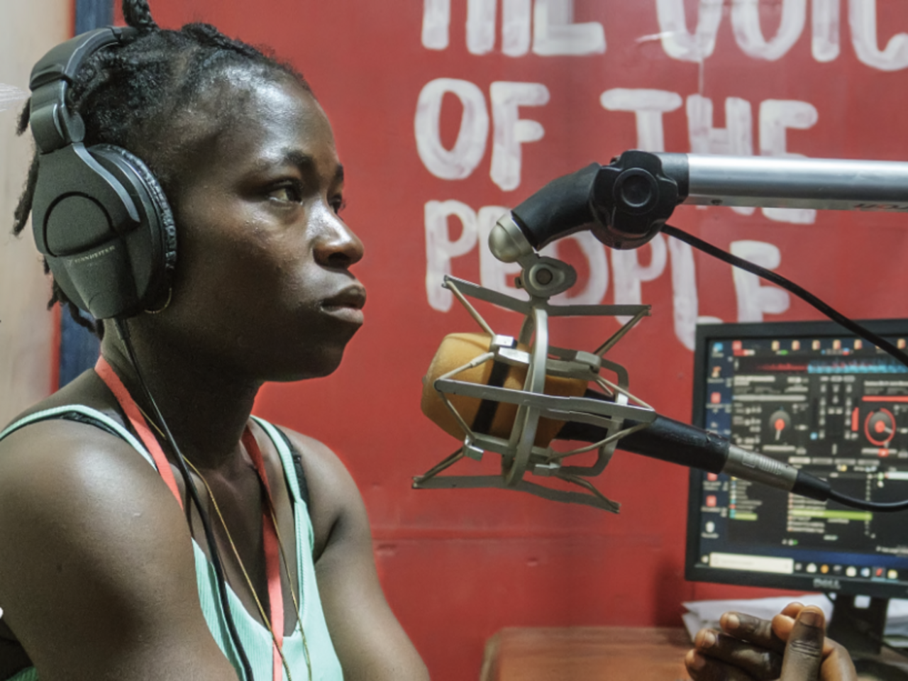 A woman in a radio studio sits in front of a mic