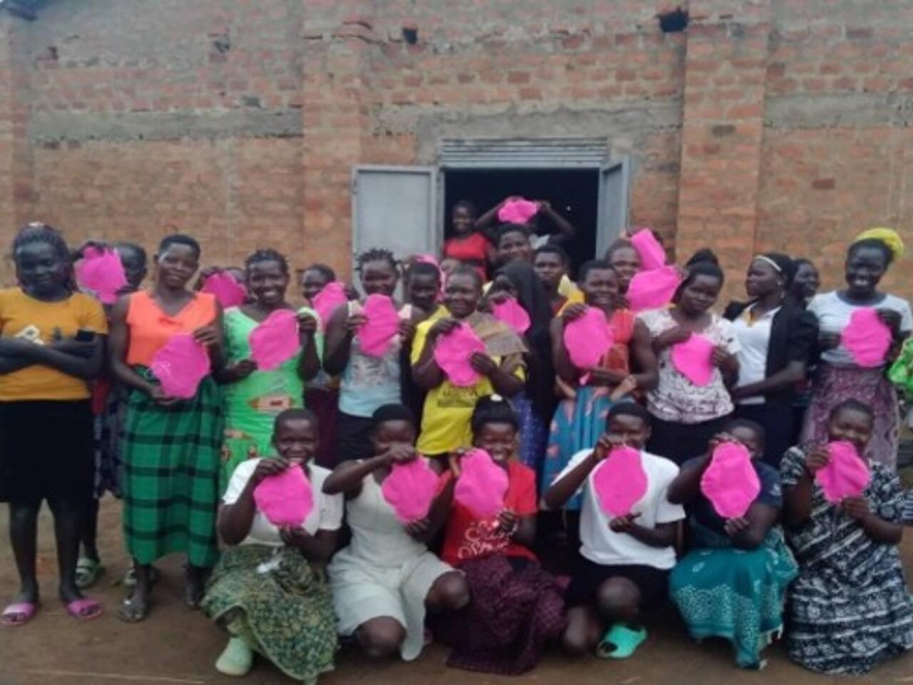 A group of smiling girls proudly display the sanitary pads they have sewn.