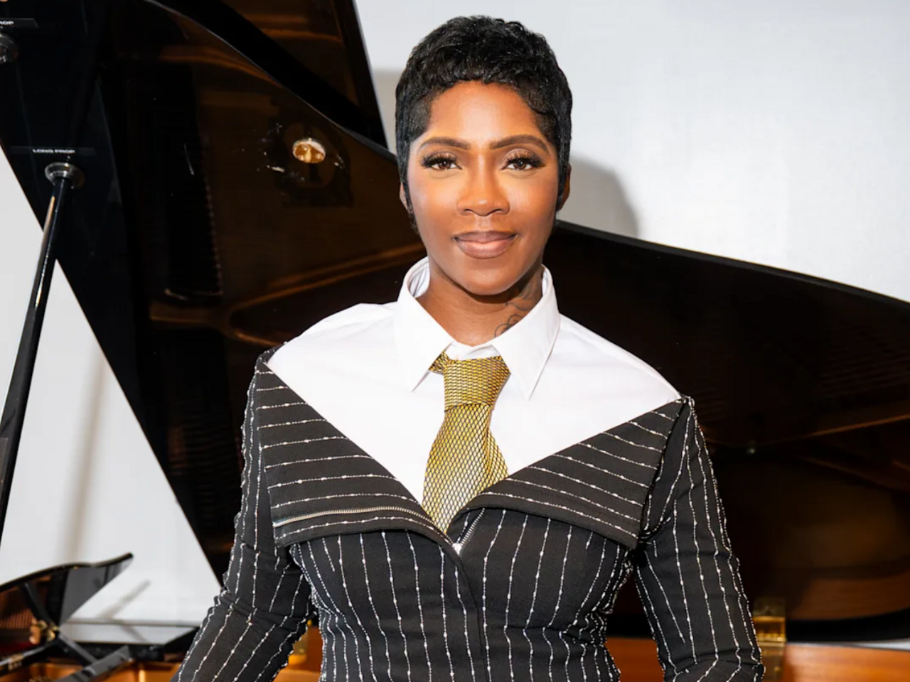Tiwa Savage standing in front of a piano