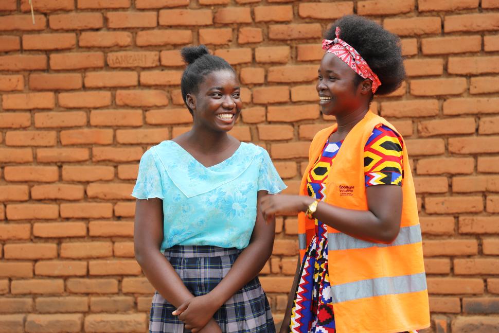 Emily standing with another girl in an orange high visibility vest 