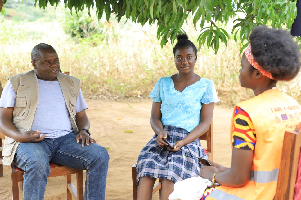 A man and two girls seated under a tree