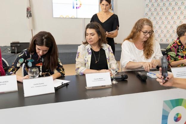 Cecilia Suarez sitting at desk with officials