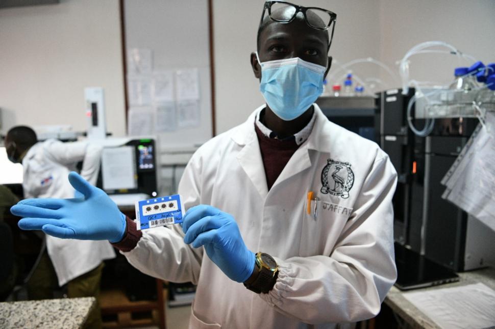Man in lab coat and mask wearing gloves