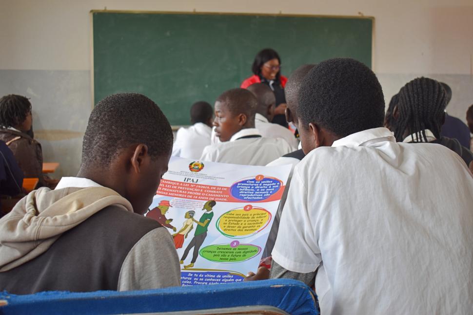 A group of students in a classroom hold a poster about the domestic violence law.