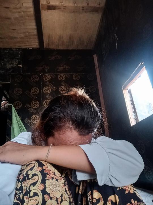 A woman sits on the floor and rests her head on her arm