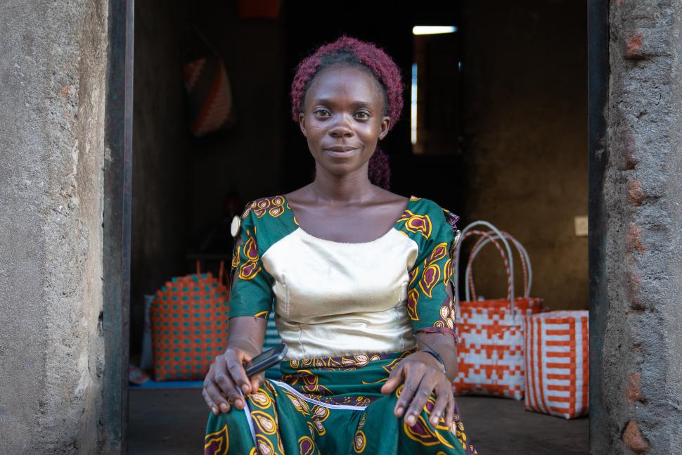 Smiling woman seated in front of shop filled with bags