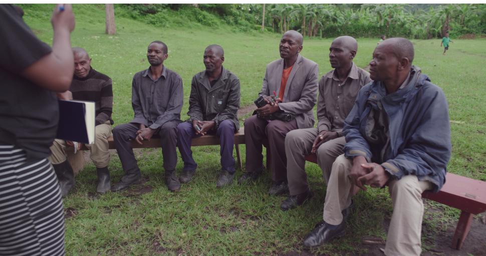 A group of seated men engaged in conversation with a female trainer