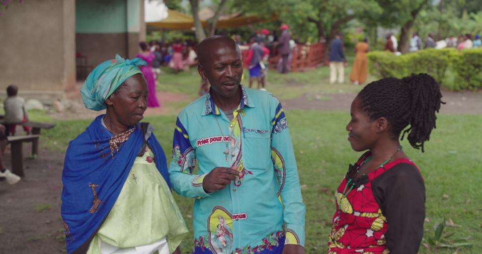 A man in a bright shirt speaking with two women