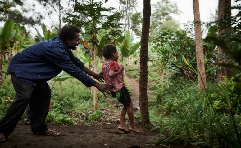 A father pushes a young child on a swing