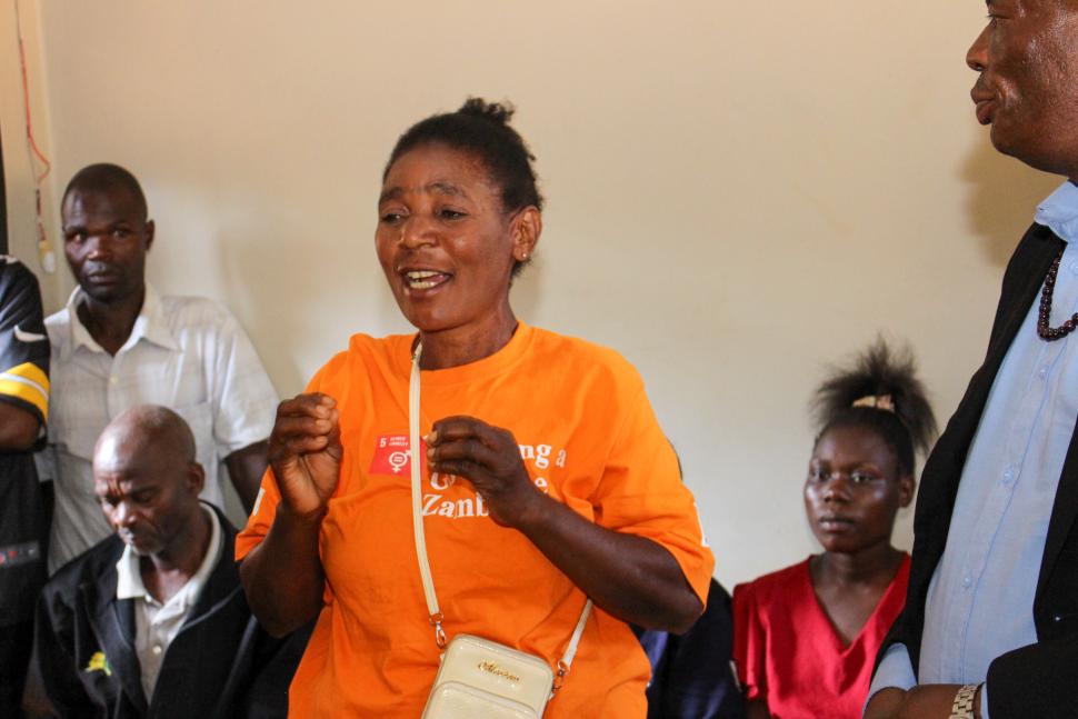 Woman in orange tee shirt speaking to audience