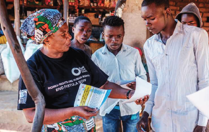 A woman handing information sheets to young men