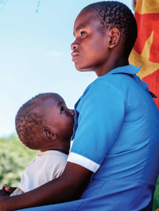 Chikondi embraces a young child who looks up at her