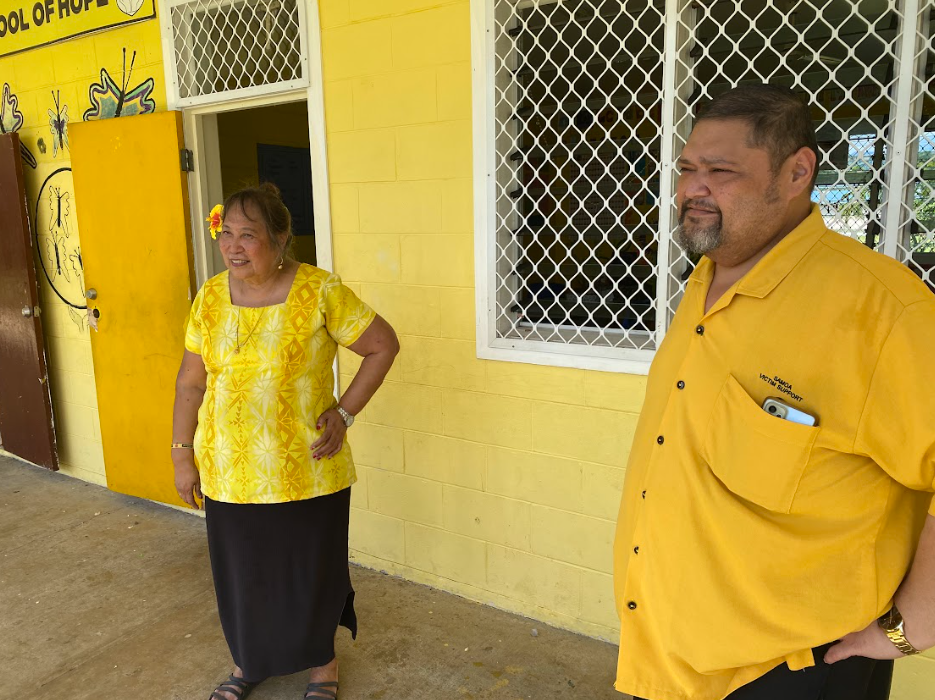 A woman and a man standing outside a yellow building