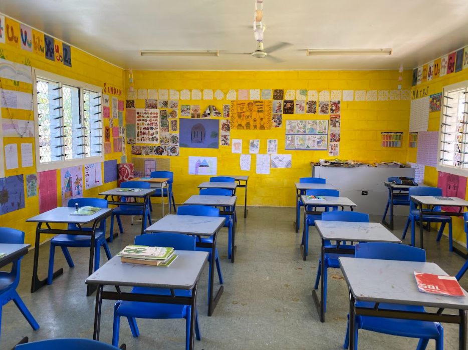 A yellow classroom with walls covered in children's art.
