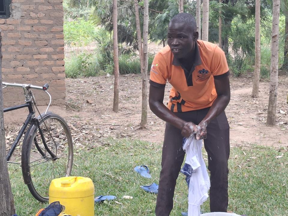 Vincent Onyango stands outside washing laundry.