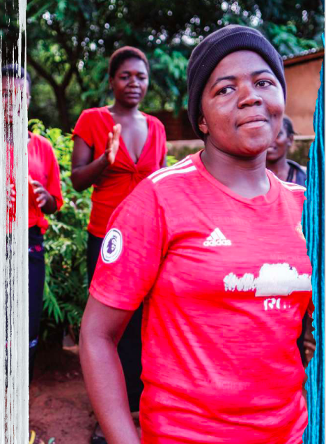 Blandina smiles in a red t-shirt and black beanie.