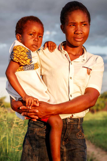 Olivia smiles and holds her young daughter on her hip