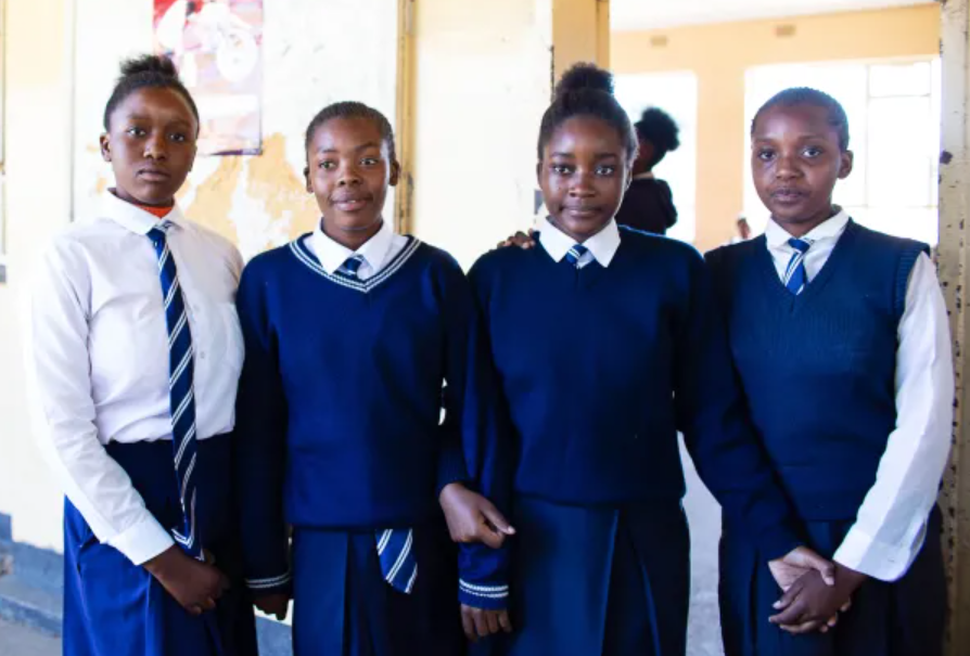 Four girls in school uniform standing beside one another
