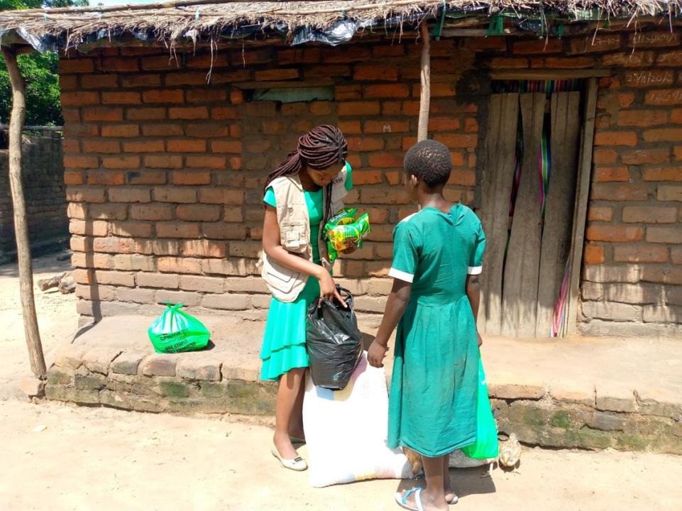 Two women wearing green speak to each other outside a building