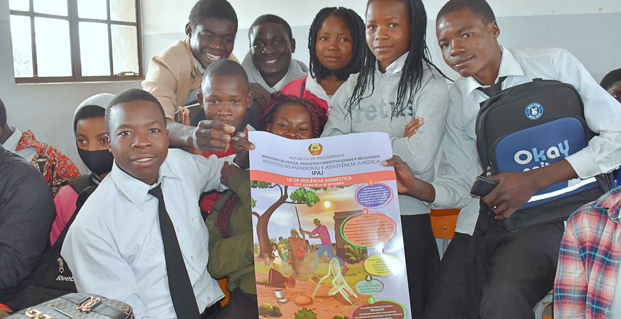 A group of students in a classroom hold a poster about the domestic violence law.