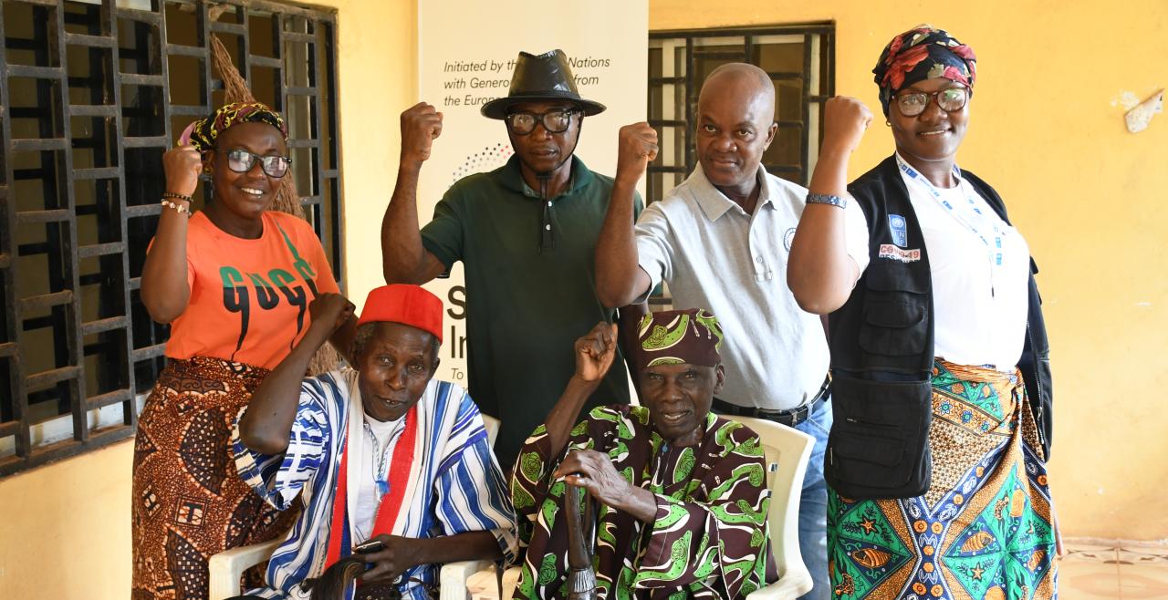 Five men and women smiling and raising fists in the air