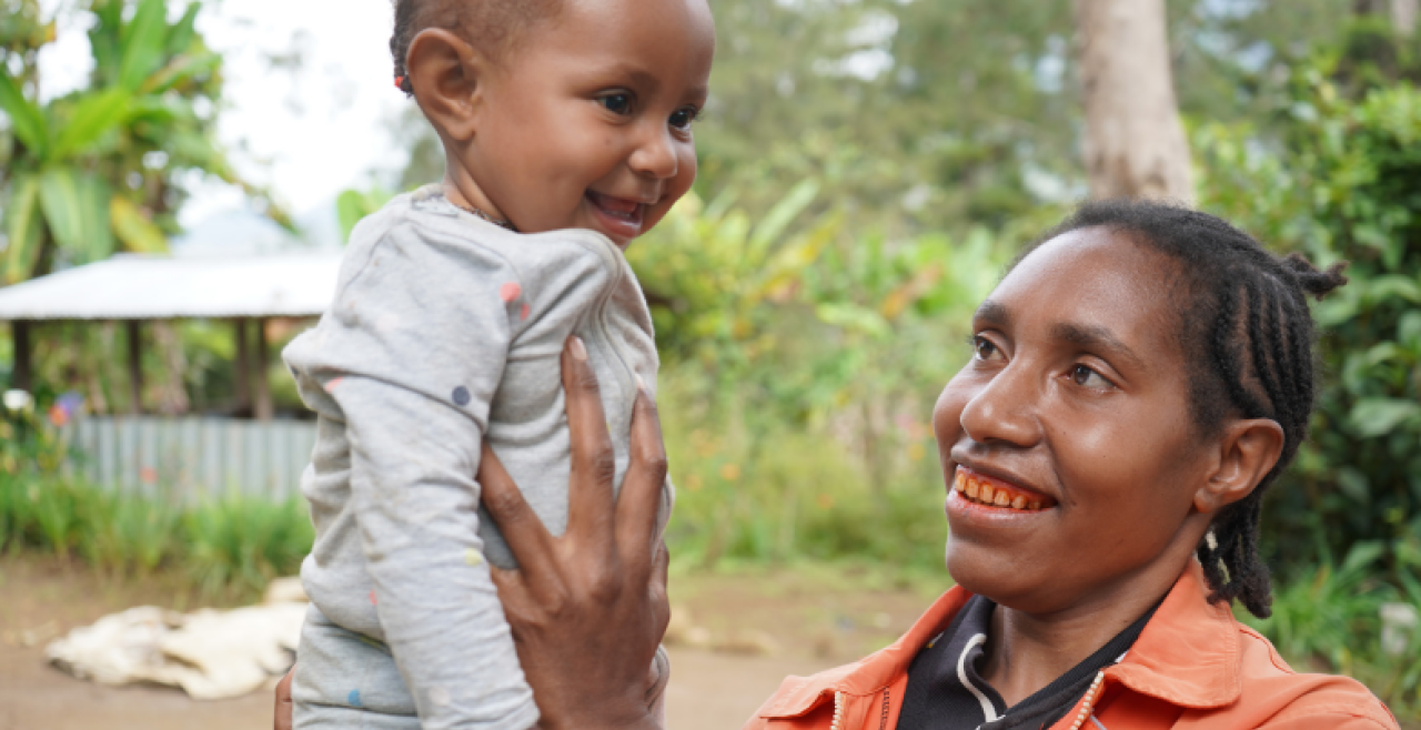 A smiling mother holds he laughing baby