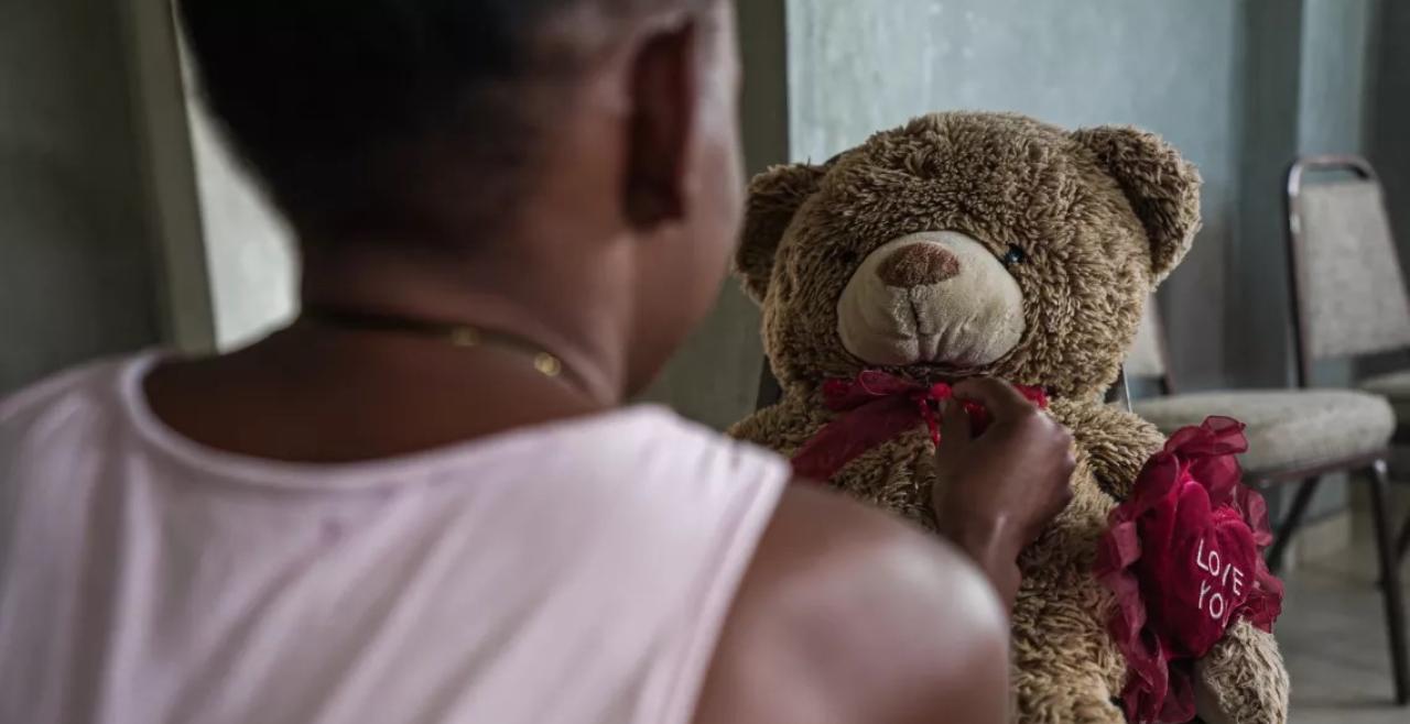 A girl photographed from behind holding a teddy