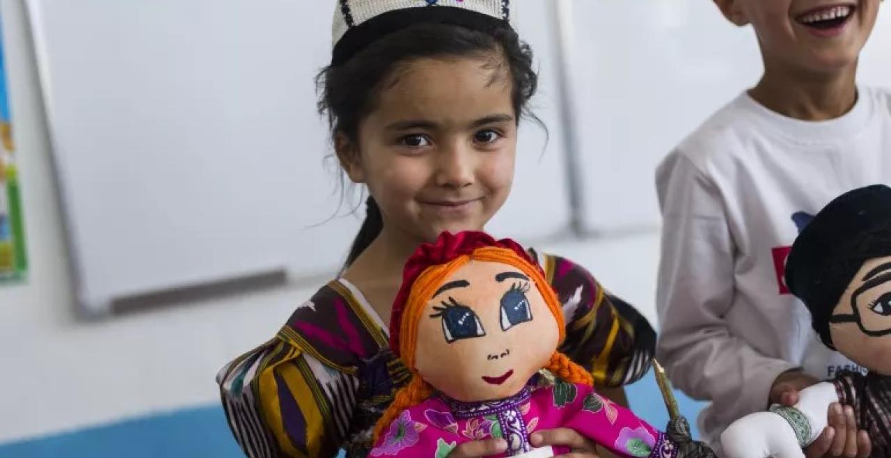 A young girl and boy smile and hold puppets