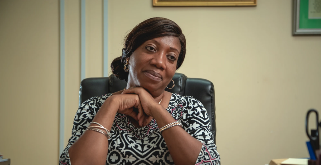 A woman in a black and white patterned shirt sitting behind a desk