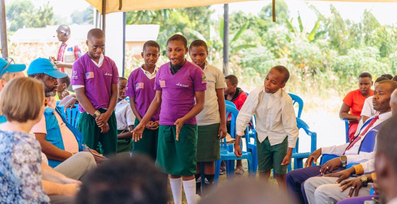 Girls in purple tshirts speaking to seated audience