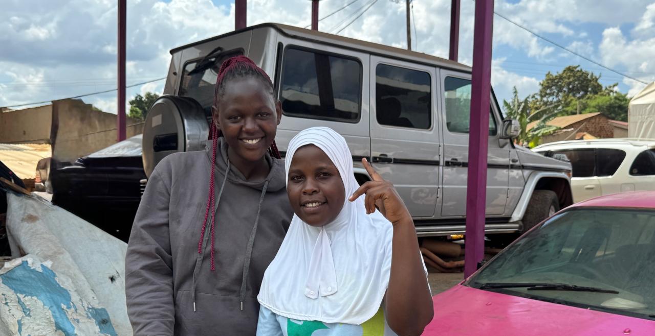 Two girls smiling in front of cars