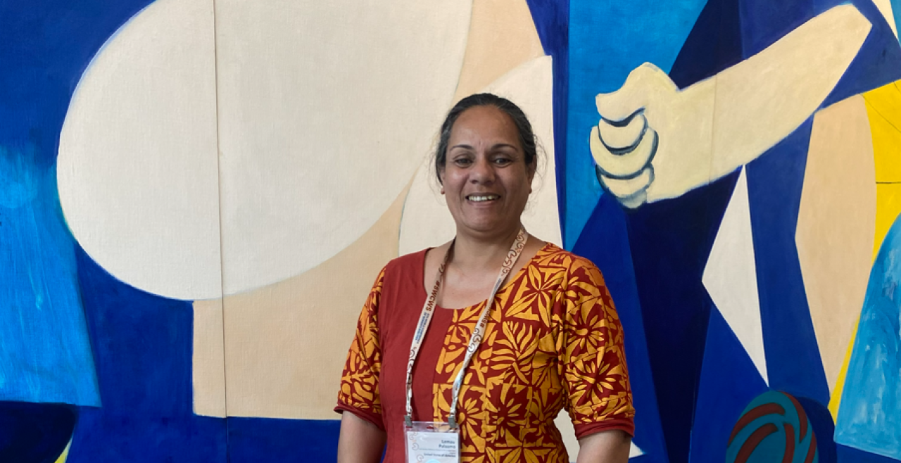 Lemau smiling in front of an abstract painting