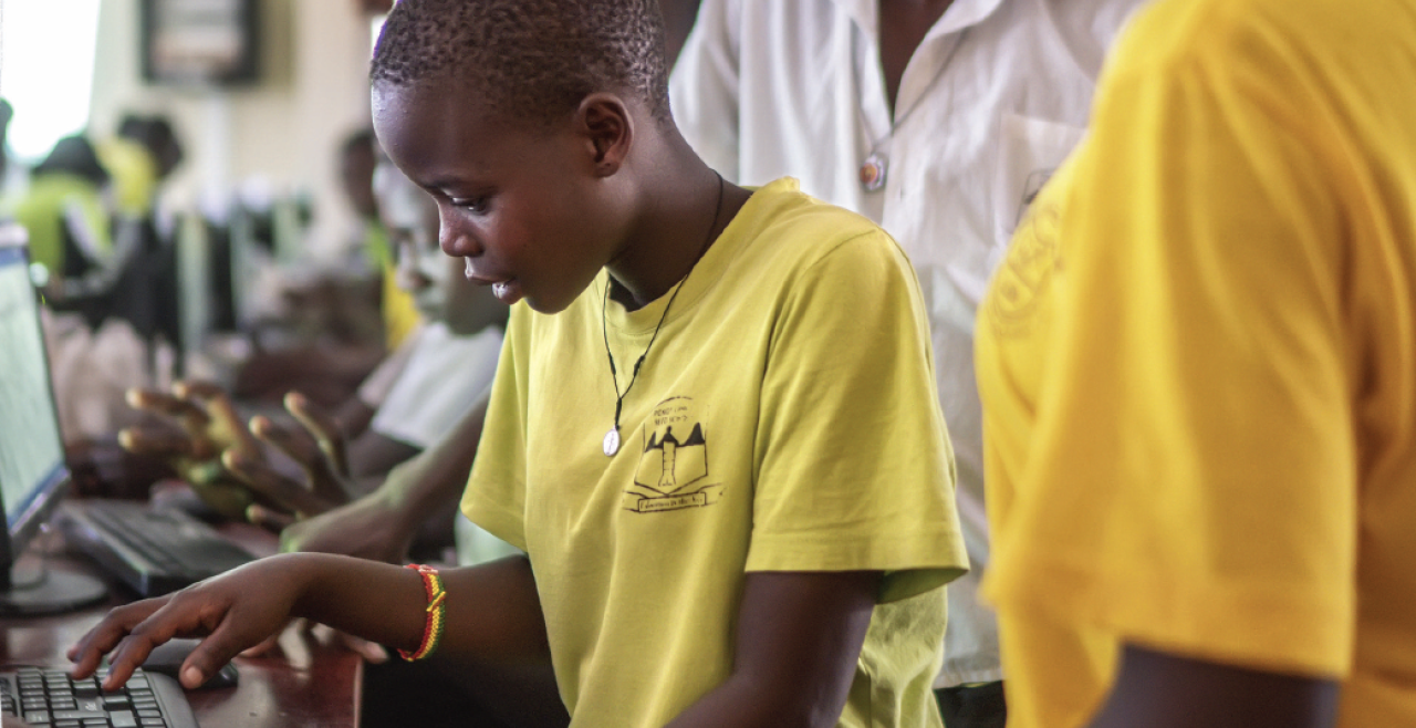 A girl in a yellow t-shirt standing at a computer