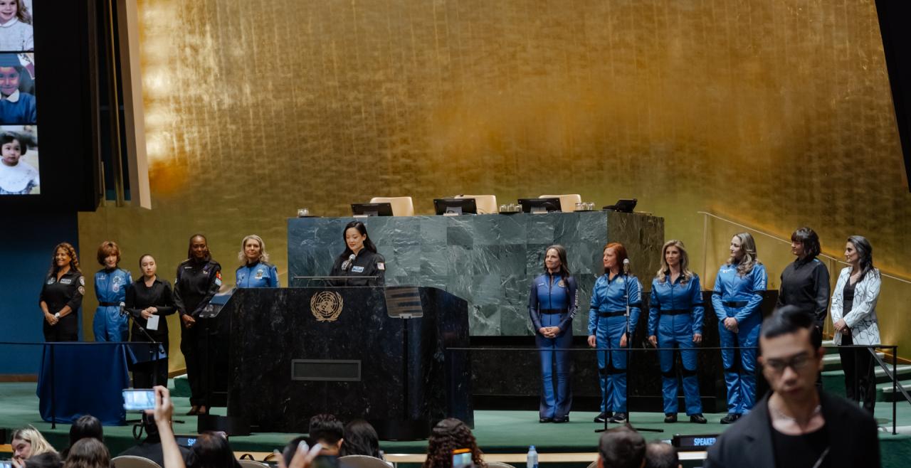 Women in astronaut suits stand at the front of the UN general assembly