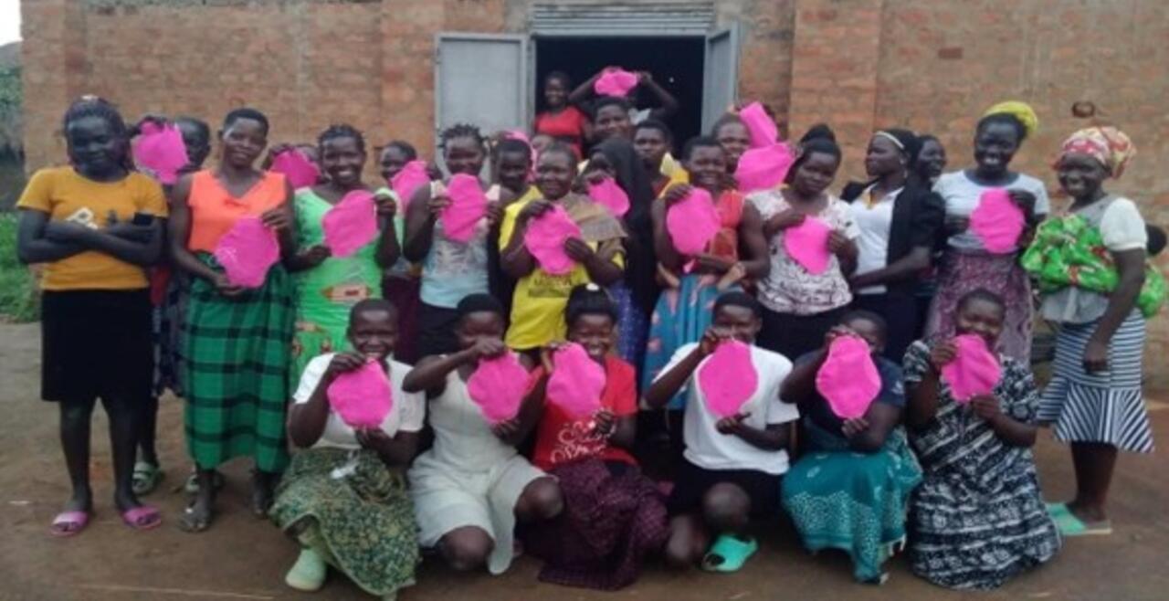 A group of smiling girls proudly display the sanitary pads they have sewn.
